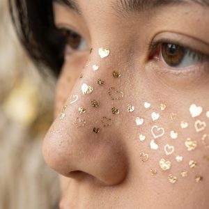 Close-up of tiny heart and star face temporary tattoos on the cheek