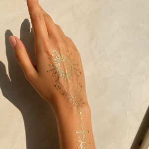 Gold sun and moon temporary tattoo worn near the ankle