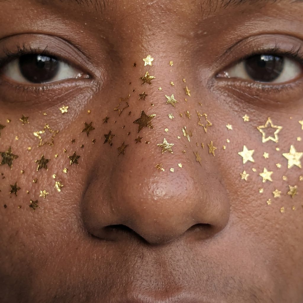 Tiny metallic star temporary tattoos worn across both cheeks