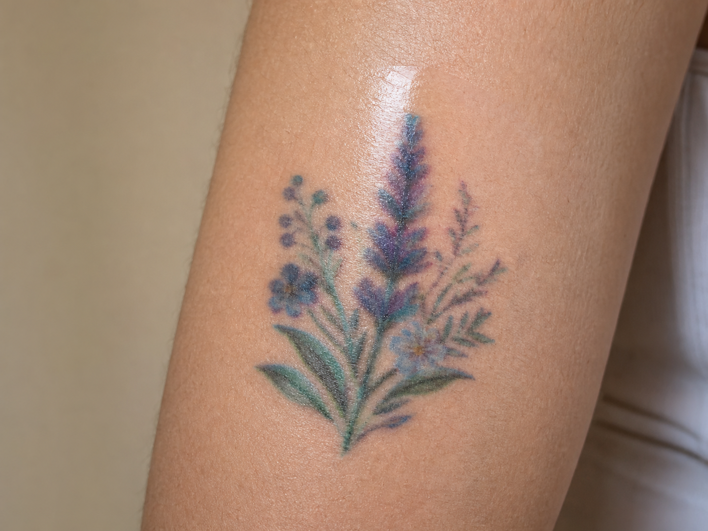 Close-up of a fictional temporary tattoo with an unnatural cool color cast and blurred printed lines on an adult arm